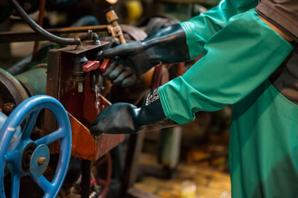 Industrial worker in protective gear handling a valve in a factory setting, ensuring safety and precision.